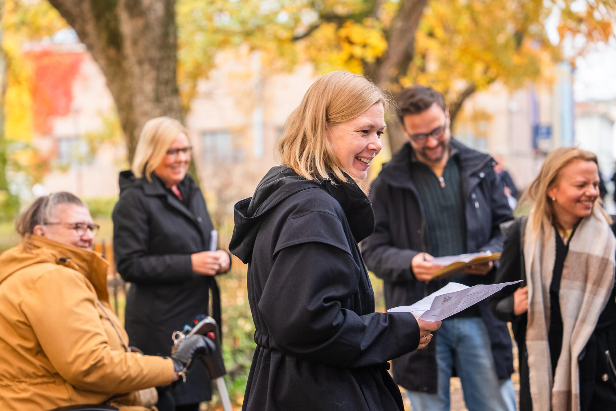 Fem personer smiler og ser på buss